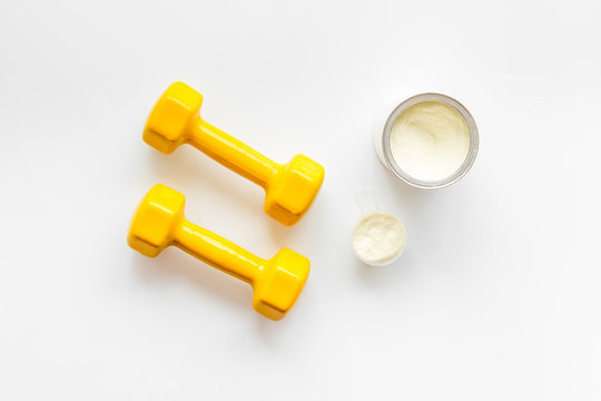 Sport diet. Protein shake near dumbbells on white background top-down flat lay