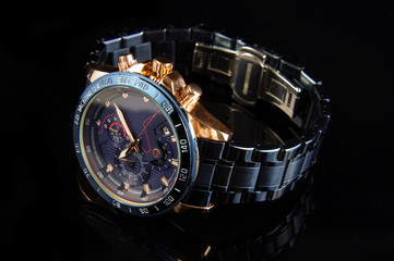 Luxury male watch on the black reflective surface