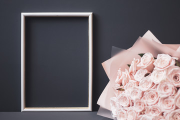Flower arrangement. Pink flowers, white photo frame on pastel gray background. Copy space.