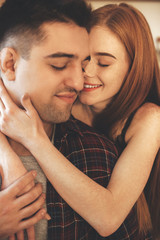 Close up portrait of a caucasian couple embracing with closed eyes and beautiful smile of a red haired woman with freckles