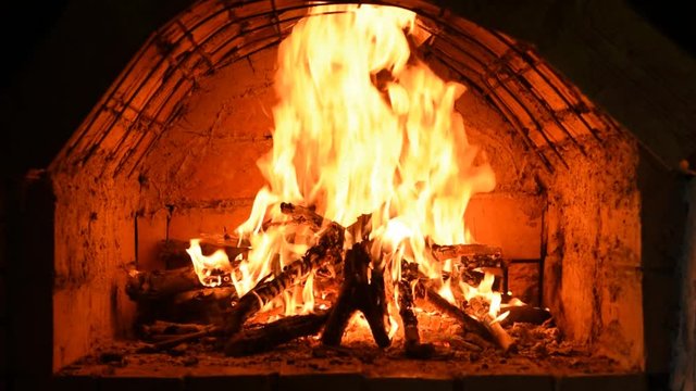 Burning fire in an old fireplace. Closeup of logs burning in flames in an ancient furnace