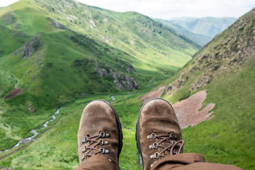 Man's feet in brown nubuck boots on a mountains background.