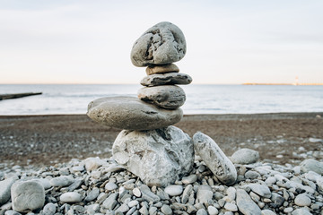 The figure of stones standing on each other, on the beach against the sea.