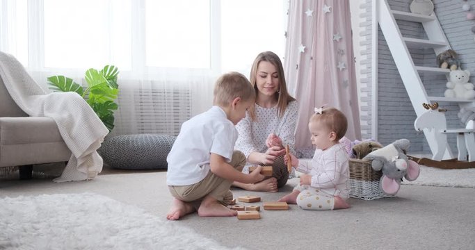 Mother and children playing with toy blocks at home