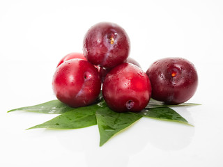 plums with plum leaves on a white background
