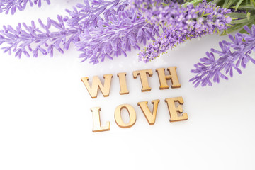 Fototapeta na wymiar Sign of love with a bunch. Purple flowers petals love text
