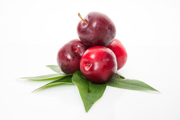 red  plum with green leaves isolated on white background