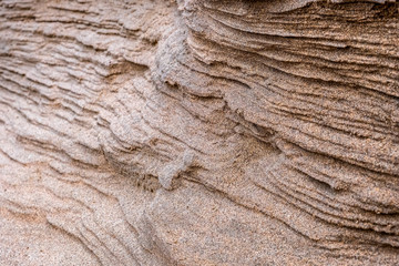 Closeup of sand with waves pattern. Beautiful natural background. Sand sea beach. Desert dunes. Abstract geometric design. Selective focus.