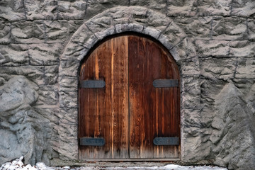 Fototapeta na wymiar Old castle stone wall with big wooden doors. Retro wooden doors castle rock, great design for any purposes.