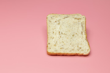 Slice of bread on a pink background. Close-up. Concept: breakfast, farm, restaurant, cafe