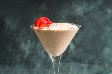 Chocolate yogurt with chia seeds and strawberry in martini glass on the rustic wooden background. Selective focus.
