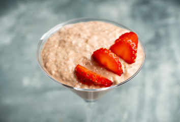 Chocolate yogurt with chia seeds and strawberry in martini glass on the rustic wooden background. Selective focus.