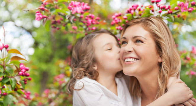 family, motherhood and people concept - happy daughter kissing and hugging smiling mother over cherry blossom background