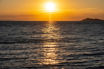 Beautiful sea sunset with island silhouette. Orange sunrise over the sea.