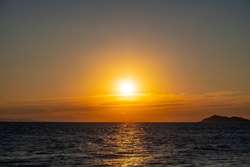 Beautiful sea sunset with island silhouette. Orange sunrise over the sea.