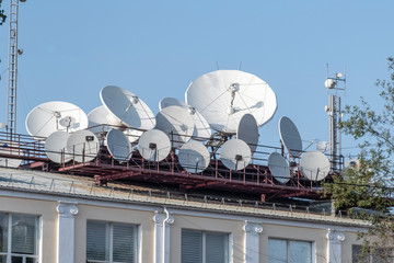A lot satellite dishes, satellite antennas mounted on the roof of building.