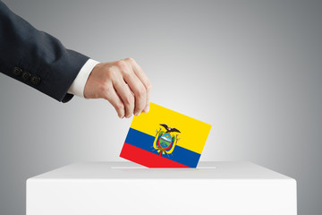 Man putting a voting ballot into a box with Ecuadorian flag.