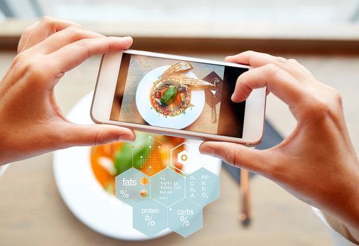 food, eating, technology, culinary and people concept - close up of hands with gazpacho soup on smartphone screen and nutritional value chart at restaurant