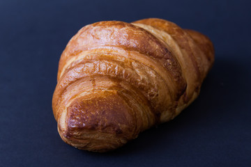Rosy croissant on black background. Bakery concept.