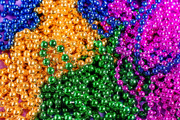 Carnival shiny beads, traditional carnaval accessories. Mardi gras frame or border on purple...