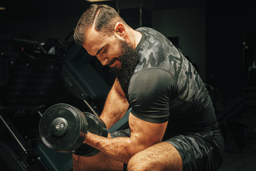 Obraz na płótnie Canvas Male with sport body lifting dumbbells at the gym