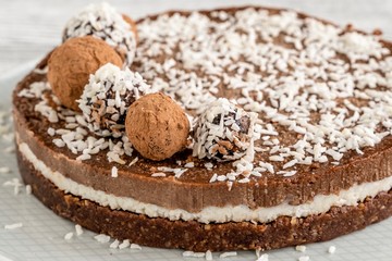 chocolate cake on a plate. Chocolate and coconut cake on a white wooden background. Foodfoto in a high key. Raw dessert