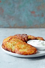 Crispy potato pancakes with green salad and yogurt sauce. Stack of potato fritters