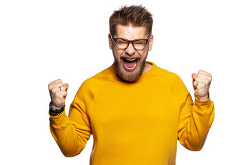 Young emotional guy exulting pleasant news. Positive boy raising and shaking fists in unrestrainable joy. 