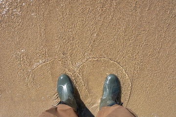 Fototapeta premium Man in brown pants and rubber boots is standing in the water. Fisherman standing in the water.