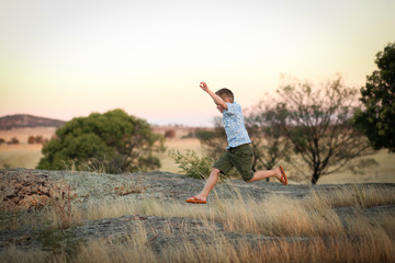Child running and jumping on rock in natural setting