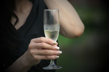 Hand of a woman holding a tall glass of white wine