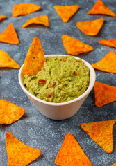 Fresh homemade hot guacamole sauce with nachos on dark background,top view