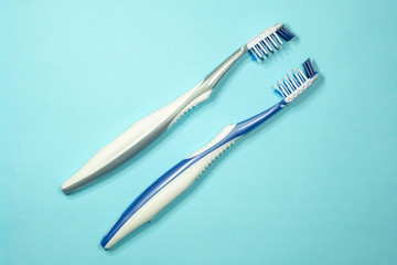 Closeup of two new plastic toothbrushes on a blue background. Dental heathcare concept.