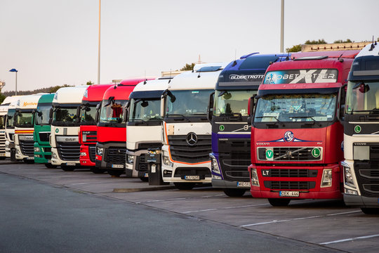 Row of various company trucks parked at a truck overnight parking somwehere along the E30 highway in Germany. E30 HIGHWAY, GERMANY - JUN 14, 2019.