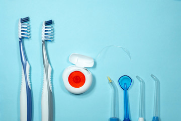 Closeup of new plastic toothbrushes, dental floss and oral irrigator on a blue background. Dental...