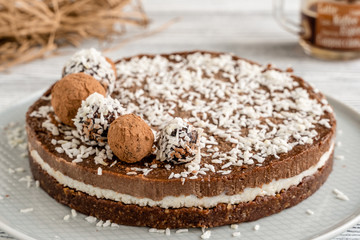 Fototapeta na wymiar chocolate cake on a plate. Chocolate and coconut cake on a white wooden background. Foodfoto in a high key. Raw dessert