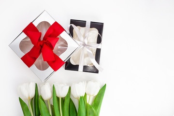 White tulips, black and silver gift boxes with ribbons on light background flat lay. Text place 8 March Happy Mothers Day Sales.Bouquet greeting card. Copy space banner.Spring website header template.