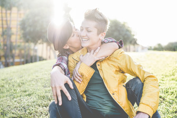 Happy gay couple having tender moments outdoor sitting on grass - Equality right, homosexuality...
