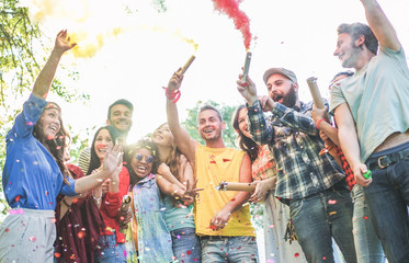 Happy friends making party,throwing confetti and using colorful smoke bombs at party outdoor - Main focus on center faces