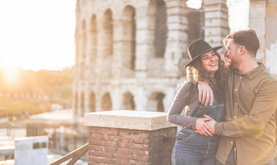 Young couple having tender moments in Rome with Colosseum as background - Focus on faces
