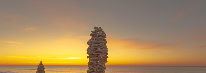 Plakat Empilement de galets sur une plage au coucher de soleil, ambiance zen.