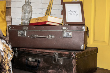 Two browh leather suitcases with books, bottle and photo frame on them.