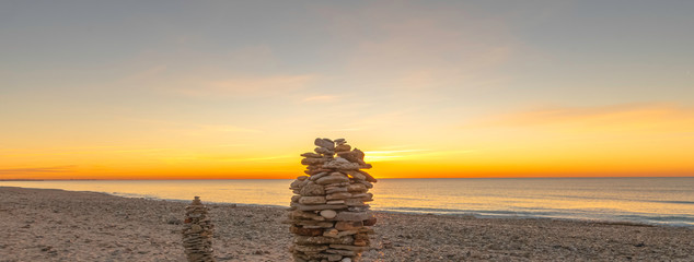 Empilement de galets sur une plage au coucher de soleil, ambiance zen.