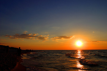 Fototapeta na wymiar Colorful sunset over beach and seashore waterline of Baltic Sea with peaceful waves in Karwia resort, north Poland, in summer season