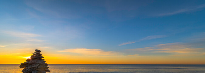 Empilement de galets sur une plage au coucher de soleil, ambiance zen.