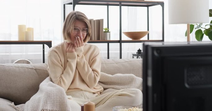 Happy woman wiping tears while watching tv and expressing her emotions