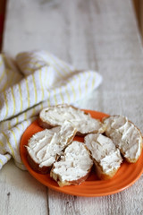 Slices of bread with cream cheese on a rustic white table. Selective focus.