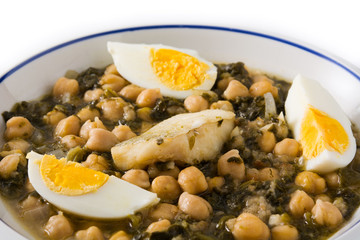 Chickpea stew with spinach and cod or potaje de vigilia isolated on white background. Close up
