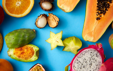 food, summer and healthy eating concept - different exotic fruits on blue background