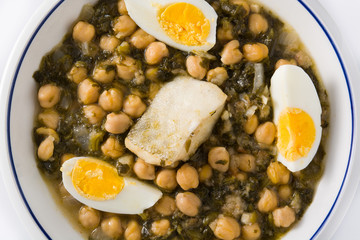Chickpea stew with spinach and cod or potaje de vigilia isolated on white background. Close up